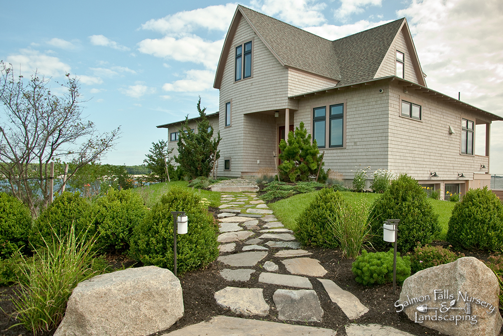Irregular stone walkway with path lighting leading to a shingle-style coastal house
